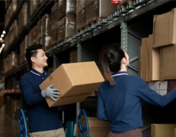 Two people in a warehouse with boxes on shelves.